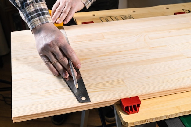 O carpinteiro marca a linha de corte na placa de madeira