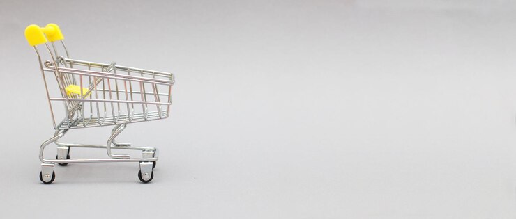 O carrinho de compras de metal em um banner de fundo cinza