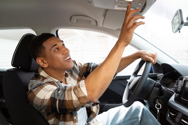 O carro apresenta um homem alegre dirigindo um carro e pressionando botões no painel do telhado testando um novo veículo sentado