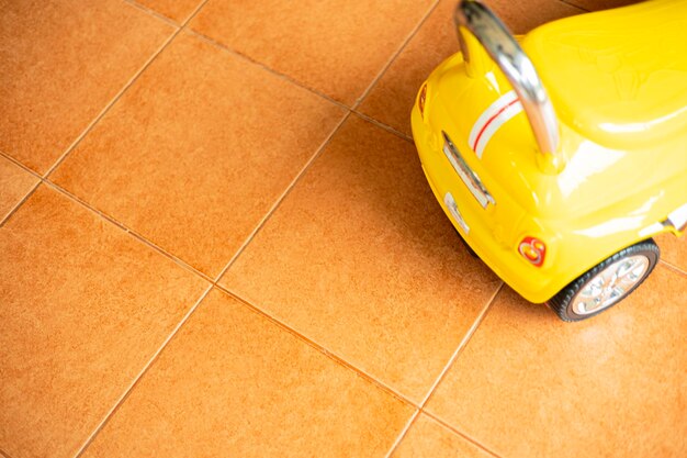 Foto o carro de brinquedo amarelo estava estacionado no chão de azulejos