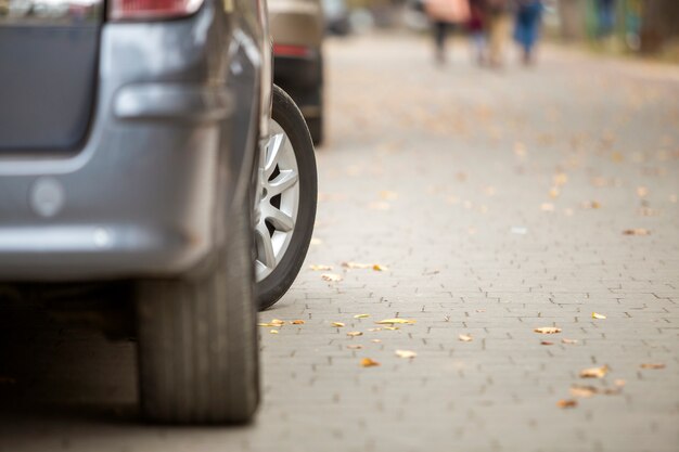 O carro de prata moderno estacionou na rua suburbana quieta ensolarada ensolarada pavimentada no dia ensolarado.