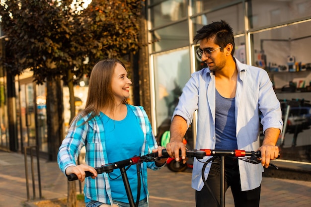 O casal apaixonado anda de patinete elétrico e olha um para o outro