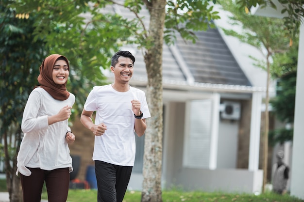 O casal asiático novo feliz exercita e aquece