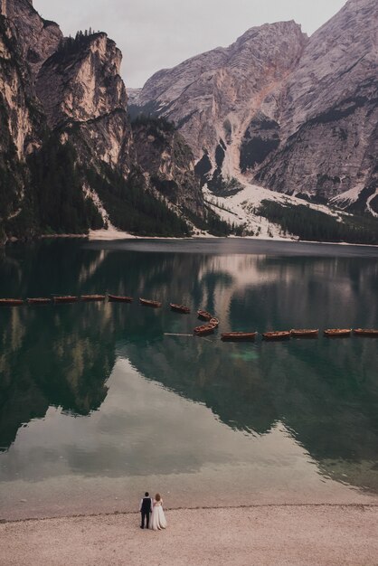 O casal de noivos está na margem de um enorme lago azul-turquesa transparente e amplo