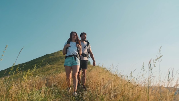 O casal de turistas caminhando com mochilas