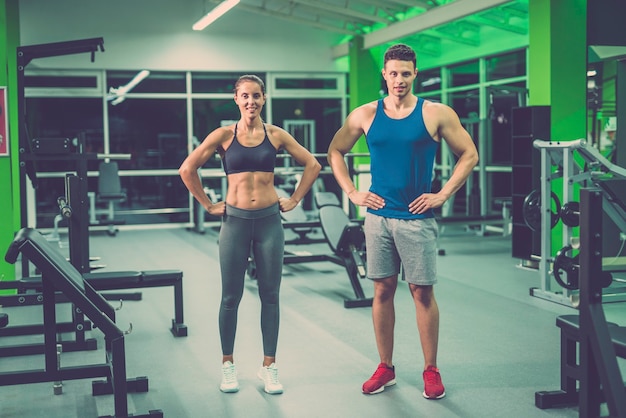 O casal esportivo fica em pé no clube de fitness