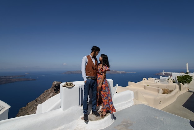 O casal está sentado no telhado em Santorini, abraçando e rindo