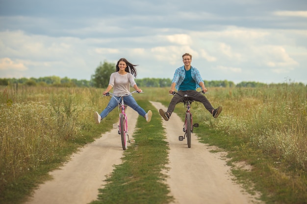 O casal feliz anda de bicicleta em um campo