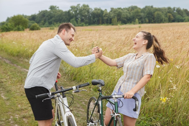 O casal feliz andando de bicicleta perto do campo