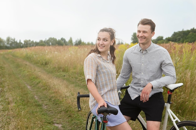 O casal feliz andando de bicicleta perto do campo