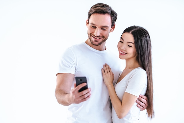 O casal feliz com um telefone em um fundo branco