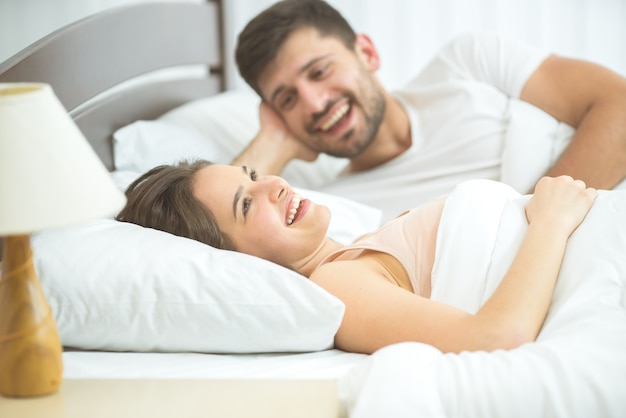 O casal feliz estava deitado na cama confortável