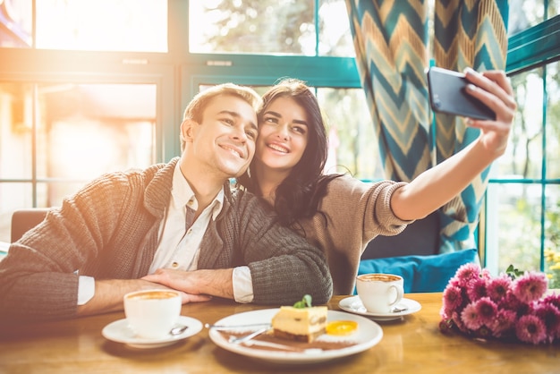 O casal feliz fazendo uma selfie em um restaurante