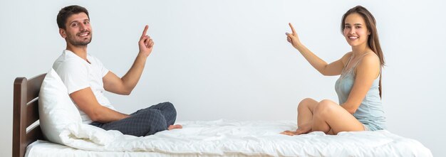 O casal feliz na cama gesticulando no fundo branco