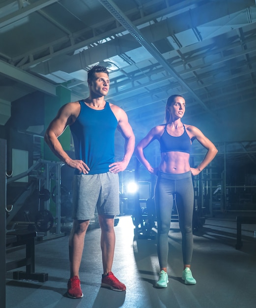 O casal fitness está na academia, no fundo claro