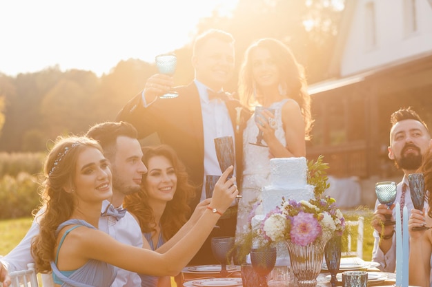 O casal recém-casado e convidados se divertem na mesa do banquete