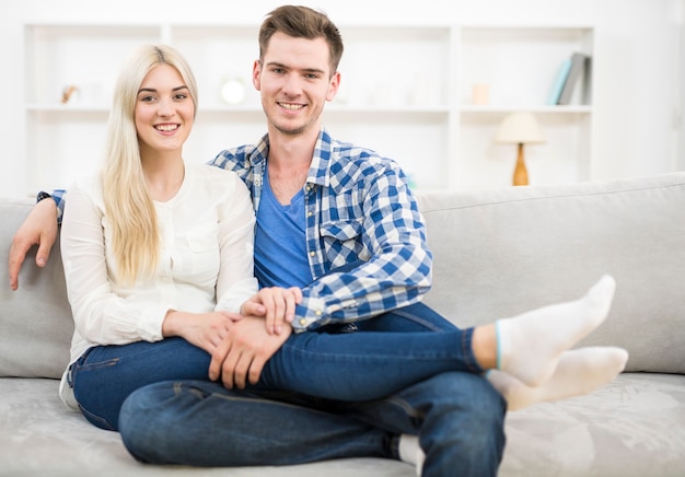 O casal sorridente descansa no sofá