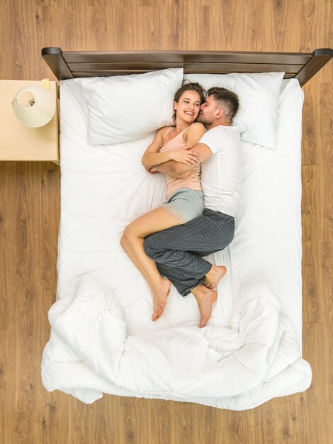 O casal sorridente estava deitado na cama. Vista de cima