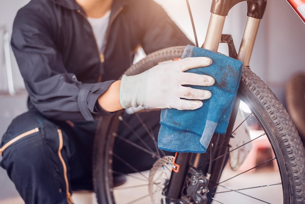 O cavaleiro da manutenção da bicicleta está limpando a bicicleta limpa Closeup