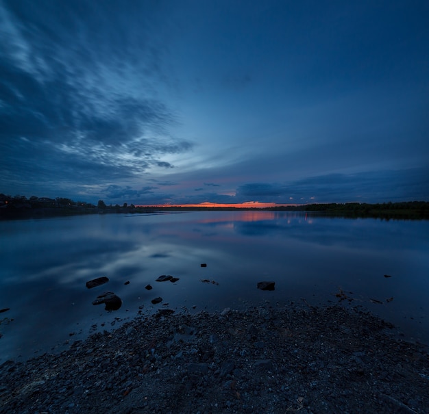 O céu ao pôr do sol refletido na água do lago.