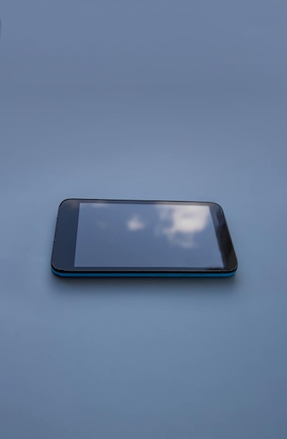O céu azul é refletido na tela de um telefone antigo danificado