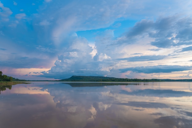 O céu bonito da noite nubla-se no por do sol no lago calmo.