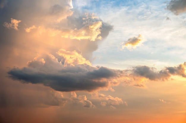 O céu dramático no por do sol com as nuvens inchado iluminou-se pelo sol de ajuste alaranjado.