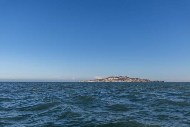 O céu está claro e azul, a ilha no meio do mar