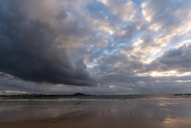 O céu está coberto de nuvens escuras e a praia está nublada.