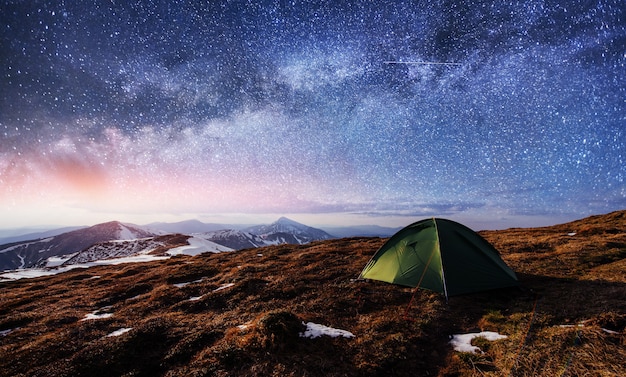 O céu estrelado acima da tenda nas montanhas.