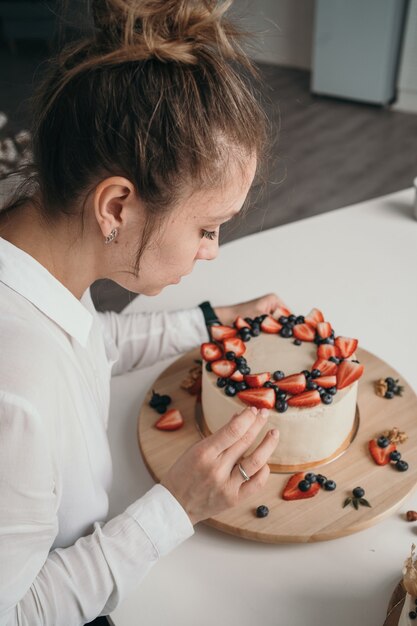 O chef confeiteiro faz um bolo em casa delicioso bolo de cream cheese com menina de frutas vermelhas aprendendo a fazer bolo