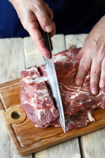 O chef corta a carne crua no tabuleiro.