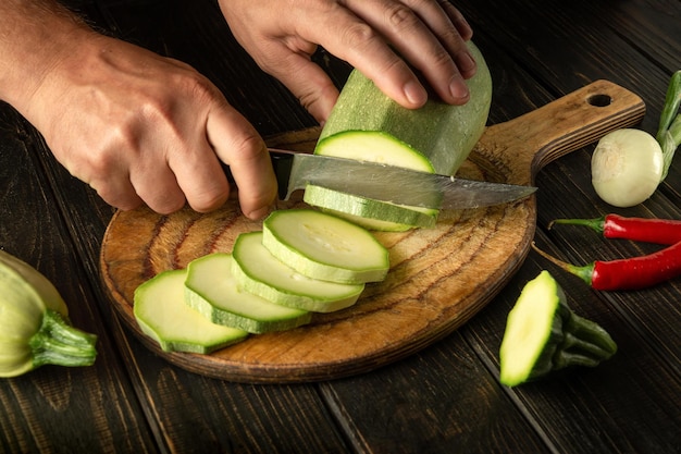 O chef corta a medula vegetal em pequenos pedaços com uma faca antes do fogo ou cozinhar comida deliciosa