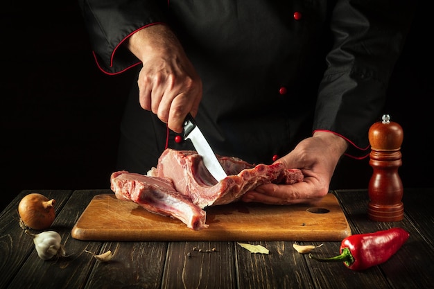 O chef corta carne crua Açougueiro cortando costelas de porco Carne com osso em uma tábua de madeira