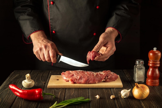 O chef corta carne crua em uma tábua antes de assar cozinha asiática Ideia de receita de menu de hotel
