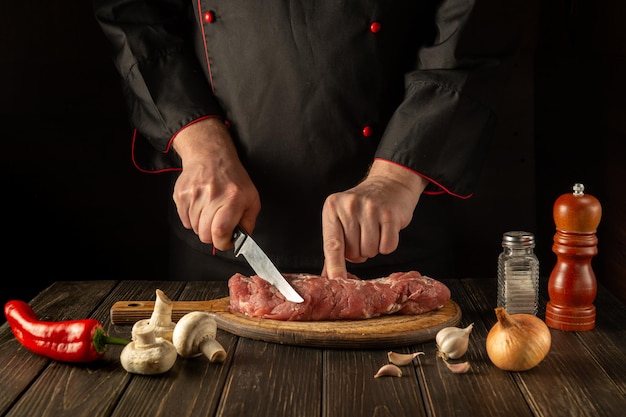 O chef corta carne de vitela crua em uma tábua de corte antes do churrasco cozinha asiática