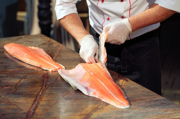 O chef corta o salmão em cima da mesa.