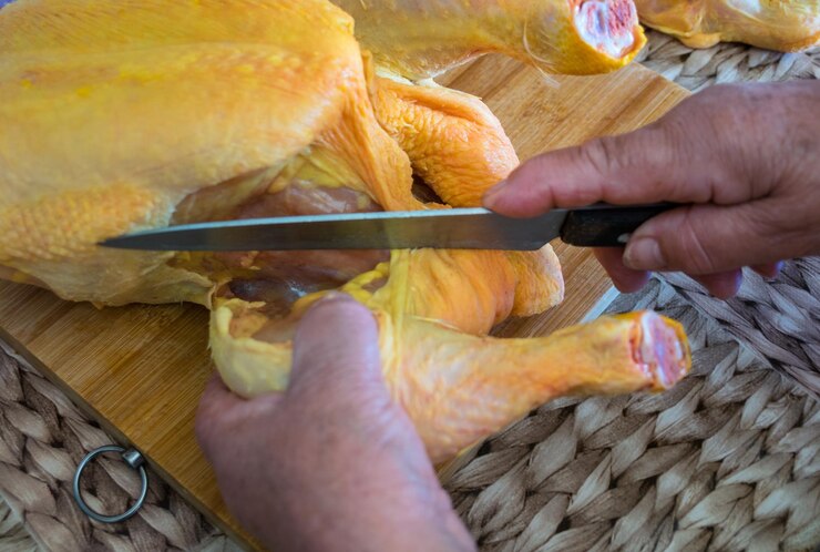 Foto o chef cortou o frango cru com uma faca.