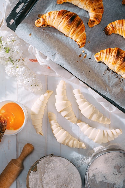 O chef cozinha croissants na cozinha de manhã na mesa croissants prontos e crus e os mesmos ingredientes para sua preparação