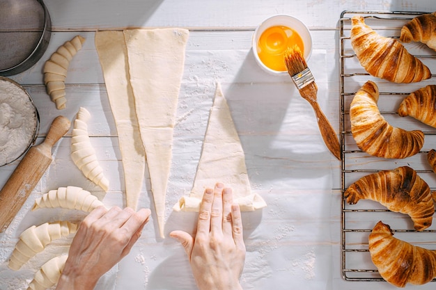 O chef cozinha croissants na cozinha de manhã na mesa croissants prontos e crus e os mesmos ingredientes para sua preparação