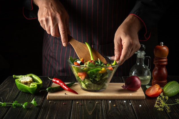 O chef cozinha uma deliciosa salada de legumes Comida vegetariana pelas mãos do cozinheiro na cozinha Ideia de menu para um hotel ou restaurante