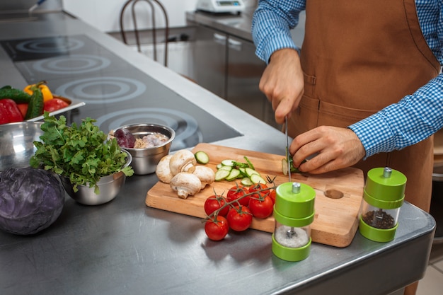 O chef de avental marrom, cozinhando em uma cozinha de restaurante