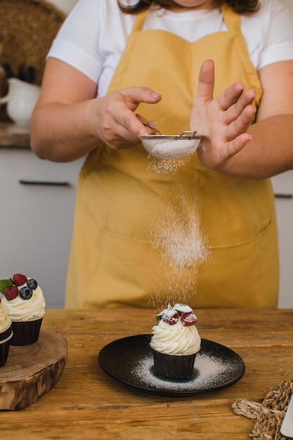 O chef de pastelaria mulher decora a sobremesa. Conceito de cursos de confeitaria ou culinária