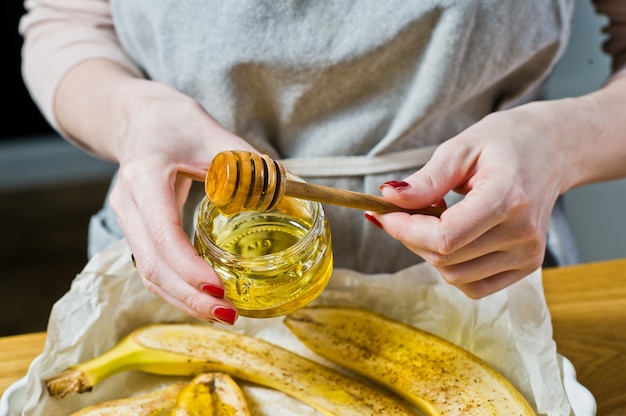 O chef derrama fatias de mel de banana em uma assadeira.