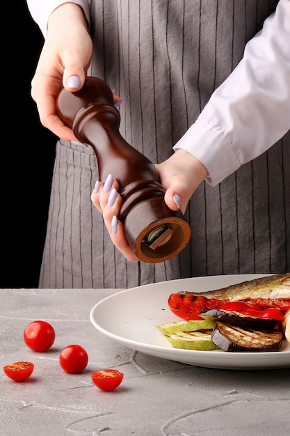 O chef está cozinhando vegetais grelhados. Pimenta. mãos femininas do chef