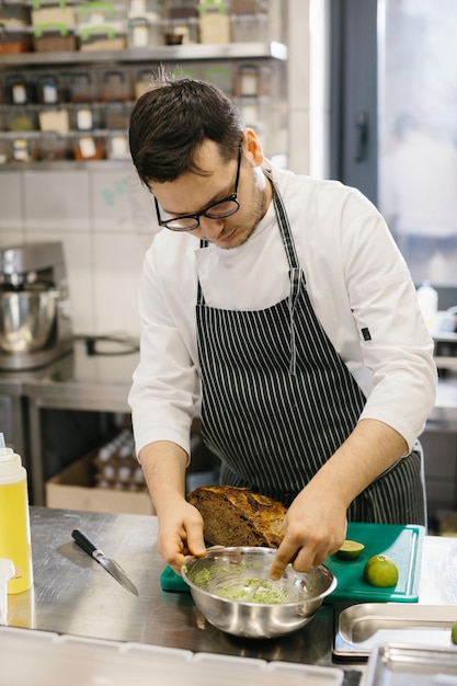 O chef está preparando comida Closeup de um chef masculino preparando torradas de abacate em uma cozinha moderna e espaçosa
