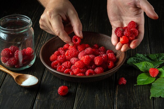 O chef está separando framboesas vermelhas frescas na cozinha para preparar um refrigerante doce Cozinhar sobremesas dietéticas