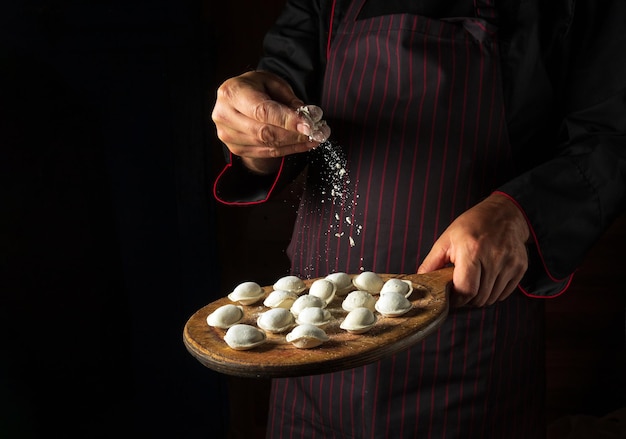 O chef joga farinha em bolinhos de carne em uma tábua Conceito para um menu de hotel