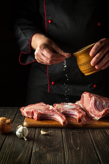 O chef joga sal na carne A ideia de cozinhar comida deliciosa para o hotel