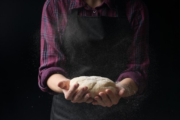 Foto o chef mantém a massa com farinha em um fundo escuro o conceito de nutrição